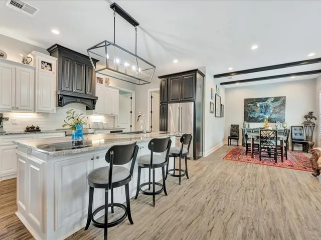 a kitchen with stainless steel appliances granite countertop a dining table chairs refrigerator sink and cabinets