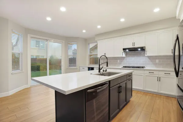 a kitchen with a sink and large mirror with wooden floor