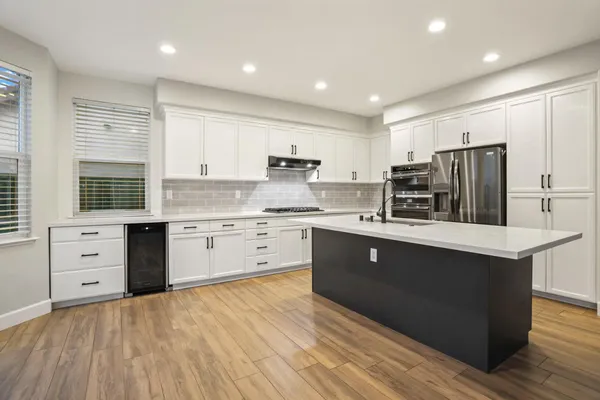 a large kitchen with granite countertop a stove a sink and a granite countertops with wooden floor