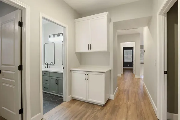 a view of an empty room with wooden floor and a ceiling fan