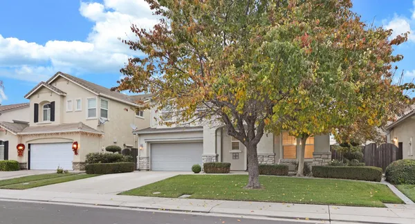a front view of a house with a garden and trees