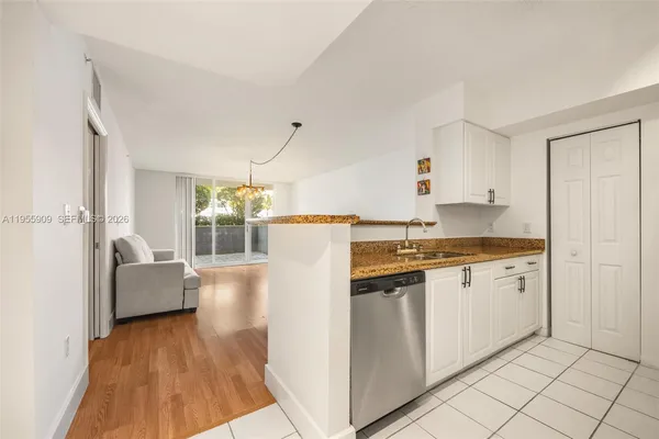 a kitchen with granite countertop a refrigerator and white cabinets