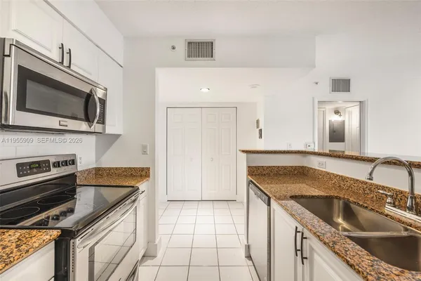 a kitchen with granite countertop a sink a stove and cabinets