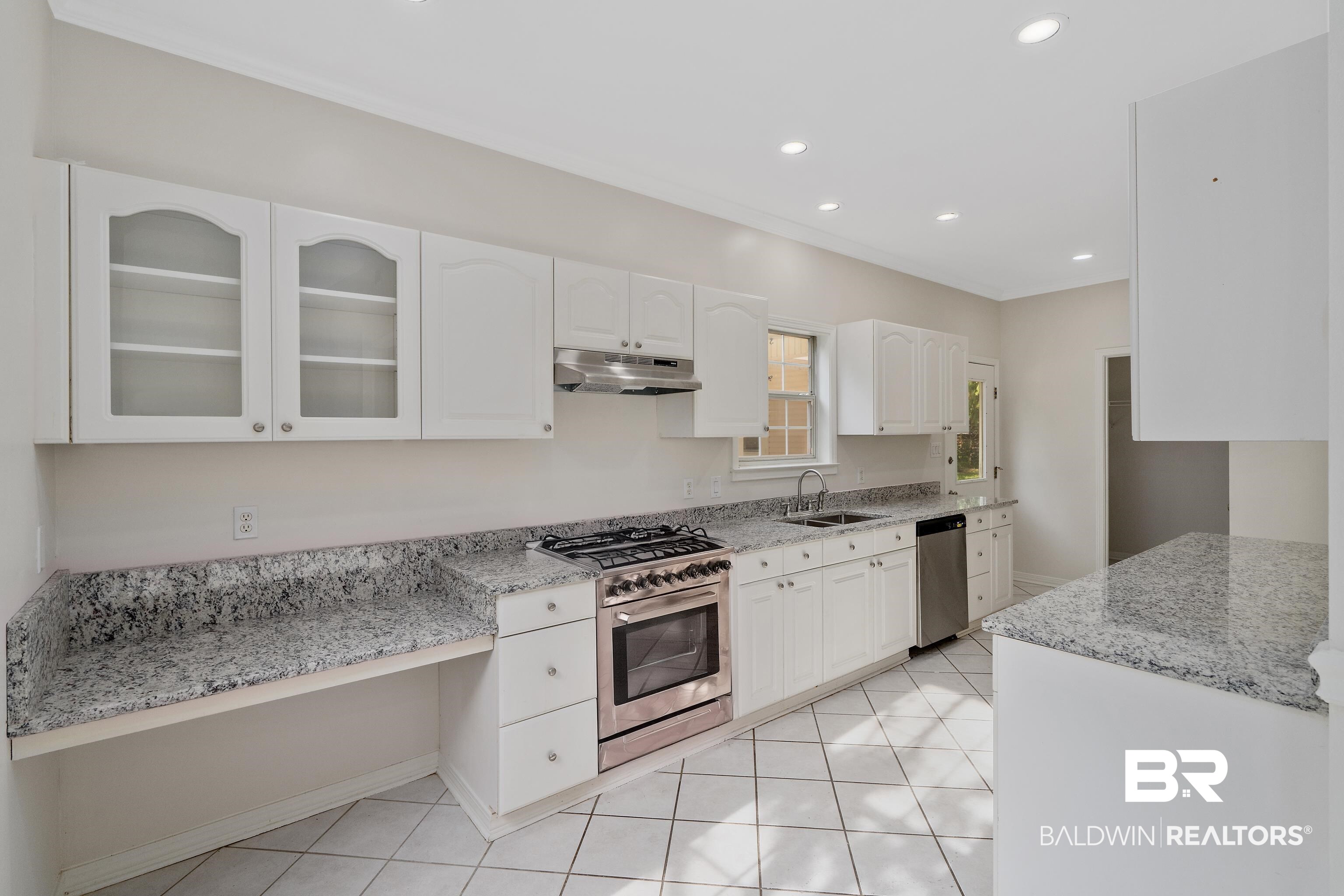 20525 Lawrence Road Fairhope, AL 36532 - Photo 9 of 26 Kitchen featuring light tile patterned flooring, white cabinets, sink, light stone countertops, and appliances with stainless steel finishes