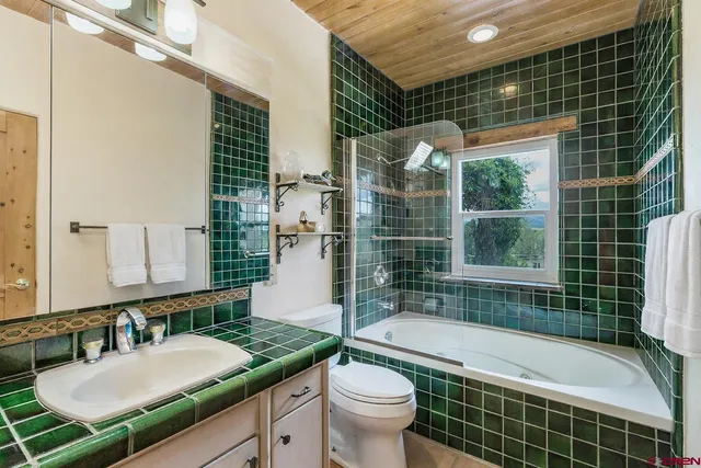 a bathroom with a granite countertop sink a toilet a mirror and shower