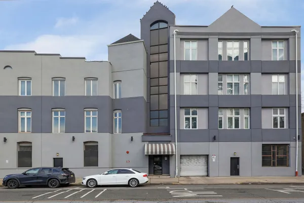 a front view of a building with lot of cars and trees