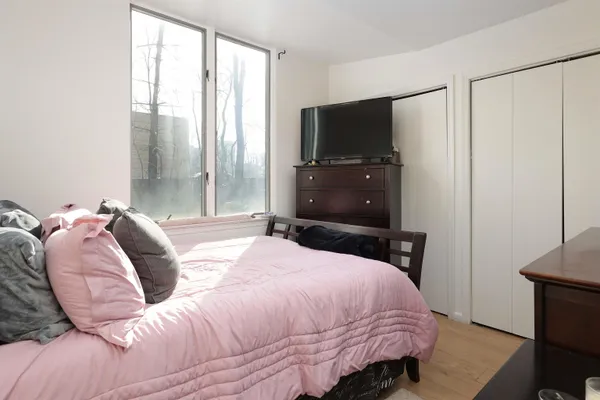 a bedroom with a bed a tv and wooden floor