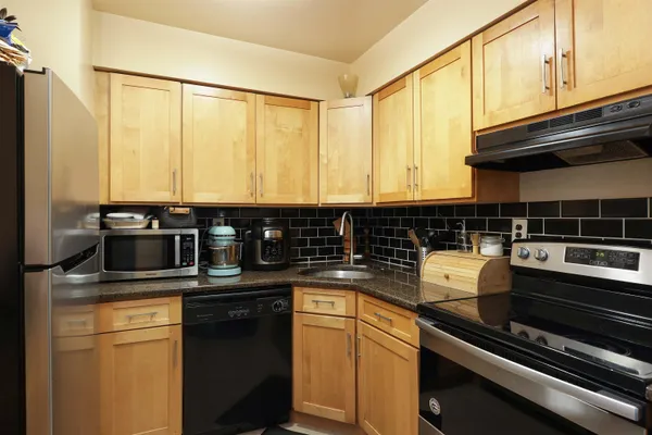 a kitchen with kitchen island granite countertop a sink cabinets and stainless steel appliances