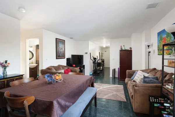 a living room with furniture a flat screen tv and a refrigerator