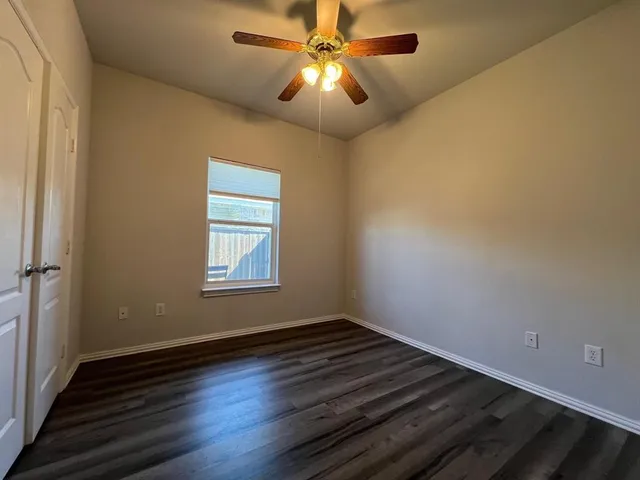 a view of an empty room with window and chandelier fan