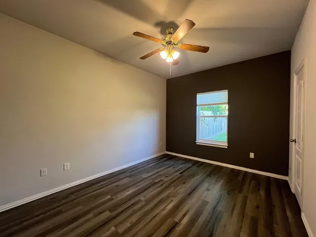 a view of an empty room with window and wooden floor
