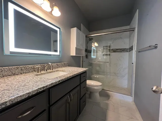 a bathroom with a granite countertop sink toilet and shower