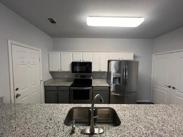 a kitchen with stainless steel appliances kitchen island sink refrigerator and microwave