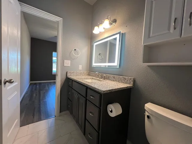a bathroom with a granite countertop sink a toilet and a mirror