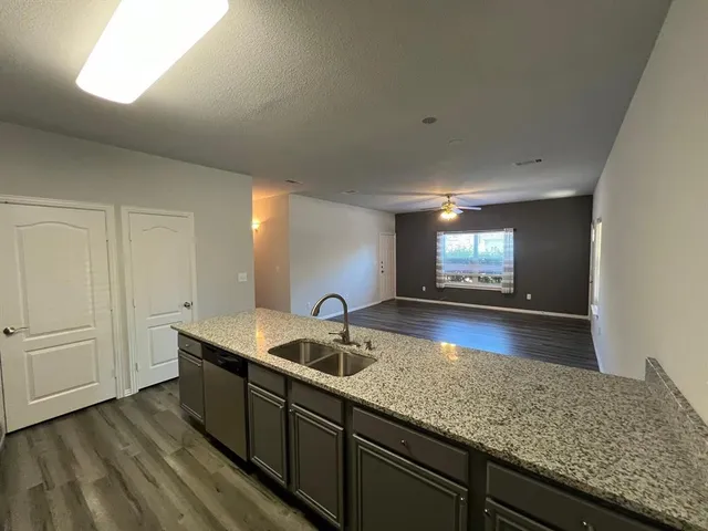 a kitchen with stainless steel appliances granite countertop a sink a stove and a wooden floors