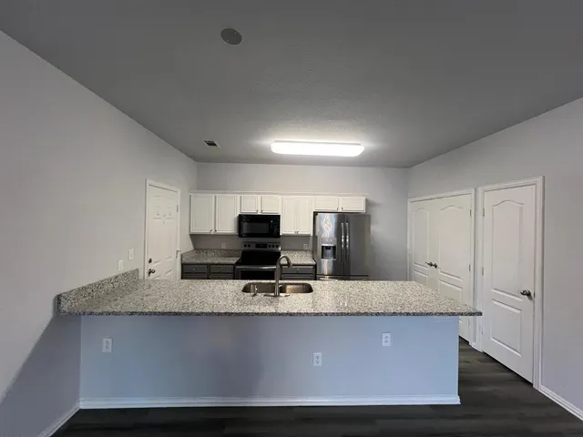 a view of kitchen with microwave stove refrigerator and cabinets