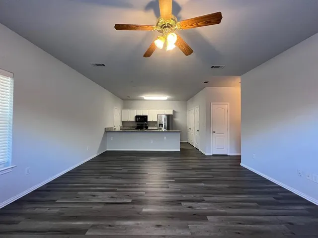 a view of kitchen and empty room with wooden floor