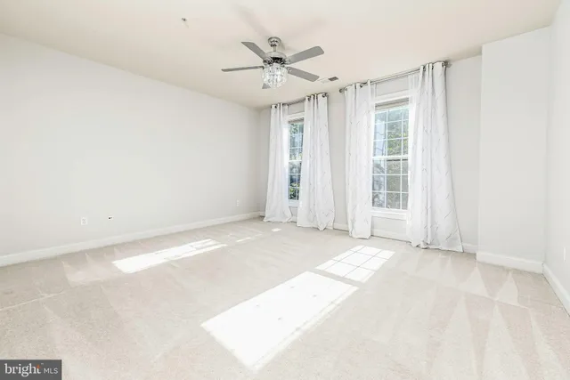 an empty room with windows and ceiling fan