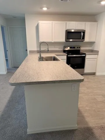 a kitchen with kitchen island a sink a stove and a microwave