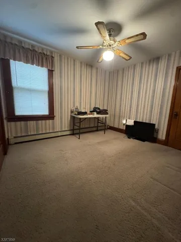 an empty room with windows and fan