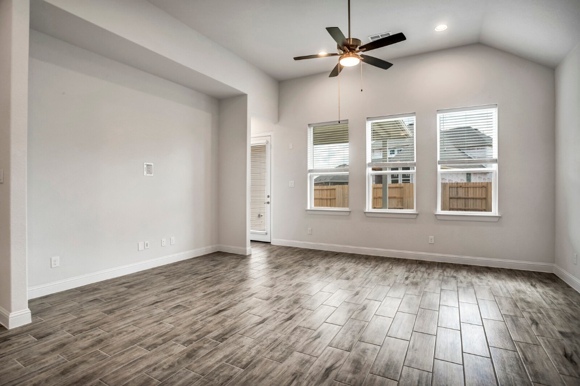 2313 Base Burner Path Leander, TX 78641 - Photo 11 of 26 an empty room with wooden floor chandelier fan and windows
