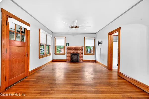 a view of an empty room with wooden floor and a window
