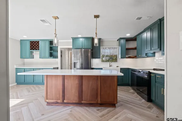 a kitchen with stainless steel appliances granite countertop a sink a stove and a wooden floors