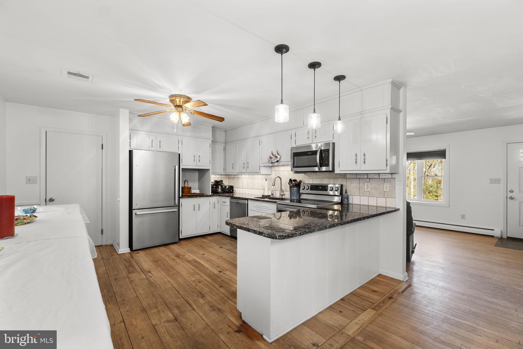 2401 Albert Rill Road Hampstead, MD 21074 - Photo 10 of 38 a kitchen with stainless steel appliances granite countertop a refrigerator a sink a stove and a wooden floors