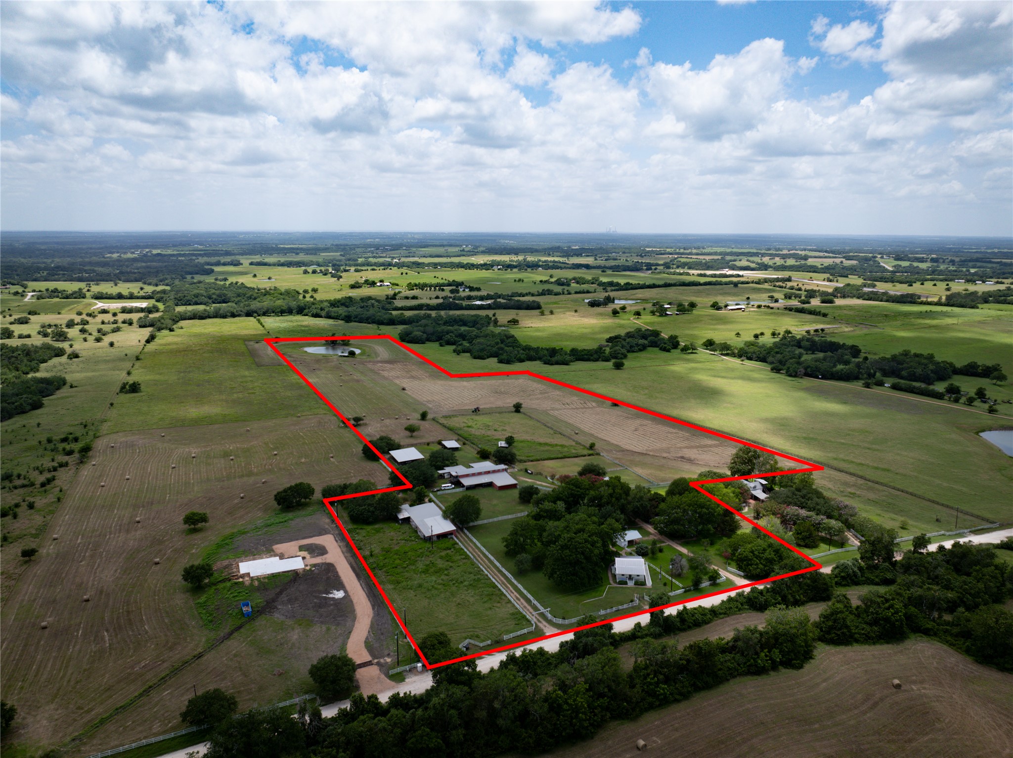 1281 Post Oak Point Road New Ulm, TX 78950 - Photo 23 of 29 Acres of verdant land offer a private pond and numerous outbuildings amidst rolling green fields.