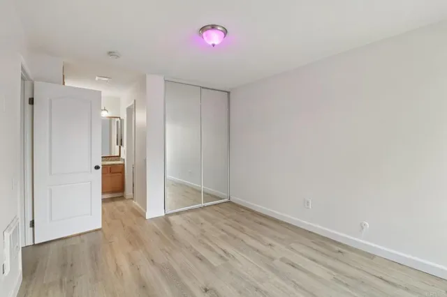 a view of an empty room with wooden floor and a bathroom