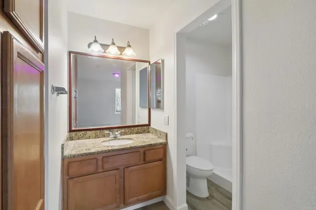 a bathroom with a granite countertop sink toilet and shower