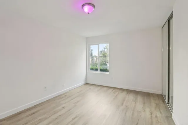 an empty room with wooden floor and windows