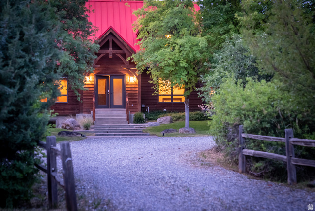 435 Canyon Road Millville, UT 84326 - Photo 88 of 113 Timber-frame home featuring a red metal roof, covered front porch, double entry doors, and mature surrounding foliage