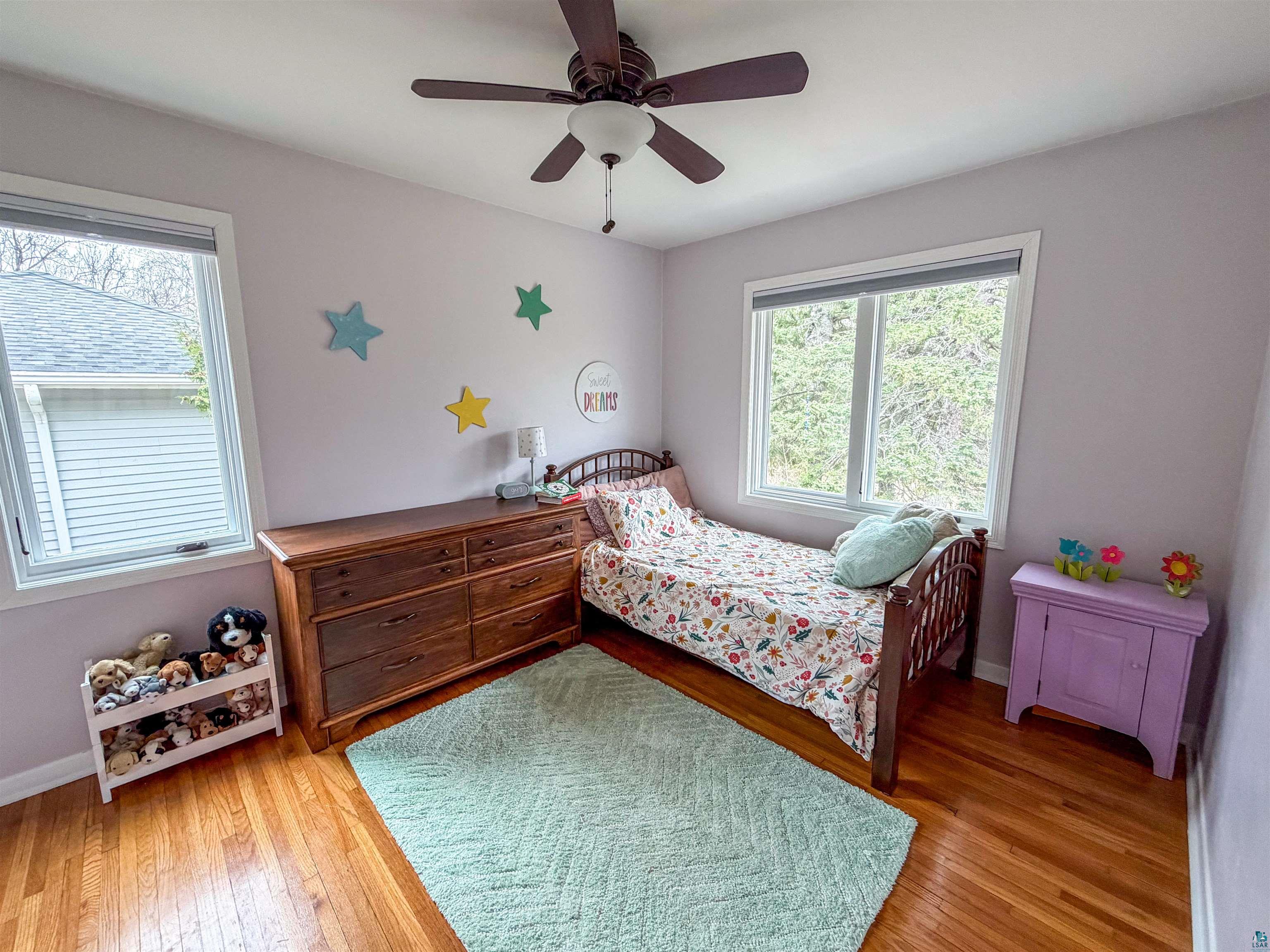 3704 Greysolon Road Duluth, MN 55804 - Photo 16 of 51 Bedroom featuring two windows, wood-finish flooring, and a ceiling fan with integrated lighting