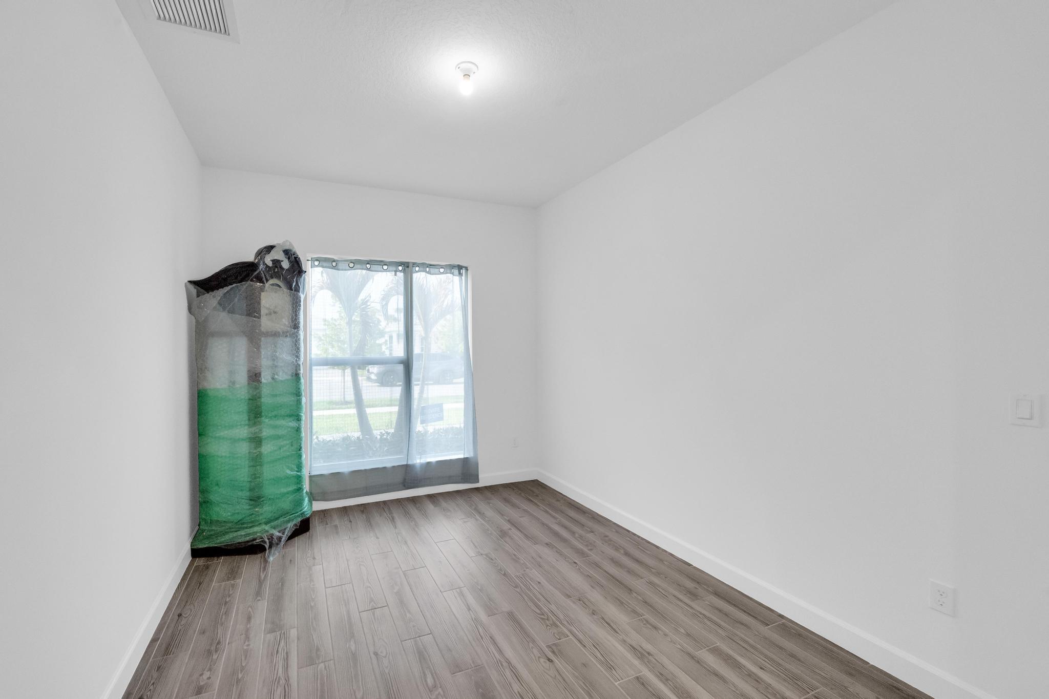 9060 Remy Lane Port St. Lucie, FL 34987 - Photo 12 of 33 an empty room with wooden floor and windows
