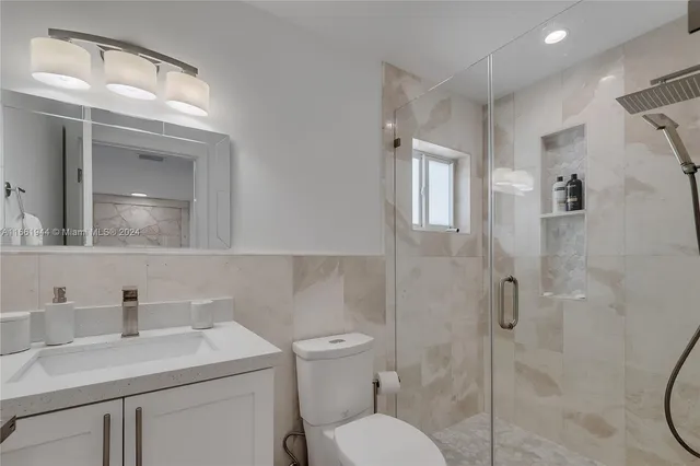 a bathroom with a toilet sink vanity granite and shower