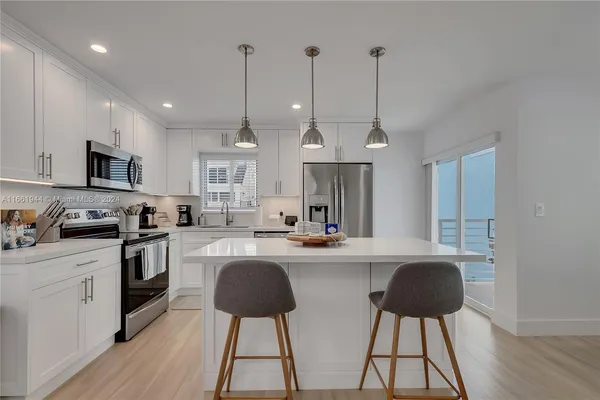 a kitchen with stainless steel appliances granite countertop a sink a stove a refrigerator cabinets and chairs