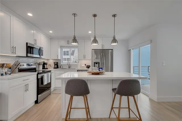 a kitchen with stainless steel appliances granite countertop a sink a stove a refrigerator cabinets and chairs