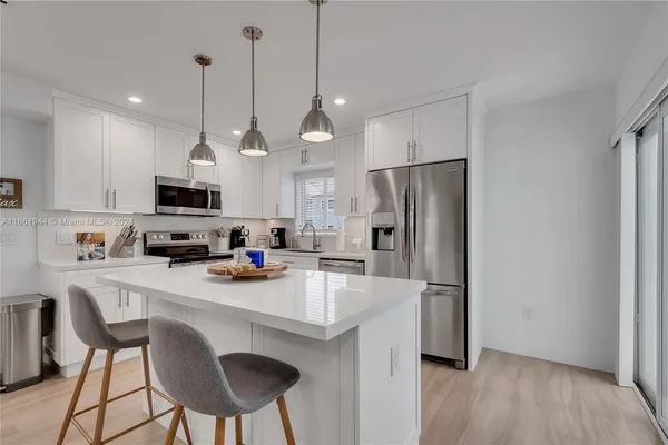 a kitchen with stainless steel appliances a refrigerator a stove a sink and a chandelier