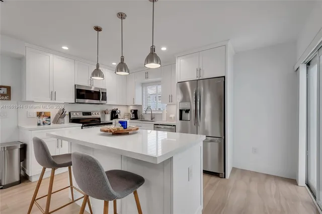 a kitchen with stainless steel appliances a refrigerator a stove a sink and a chandelier