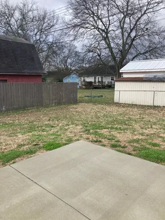 a view of a house with a yard and a large tree