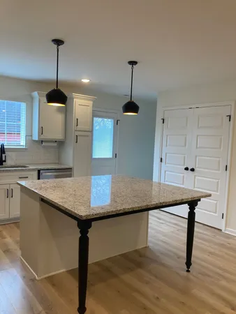 a kitchen with stainless steel appliances granite countertop a sink a stove and a wooden floor