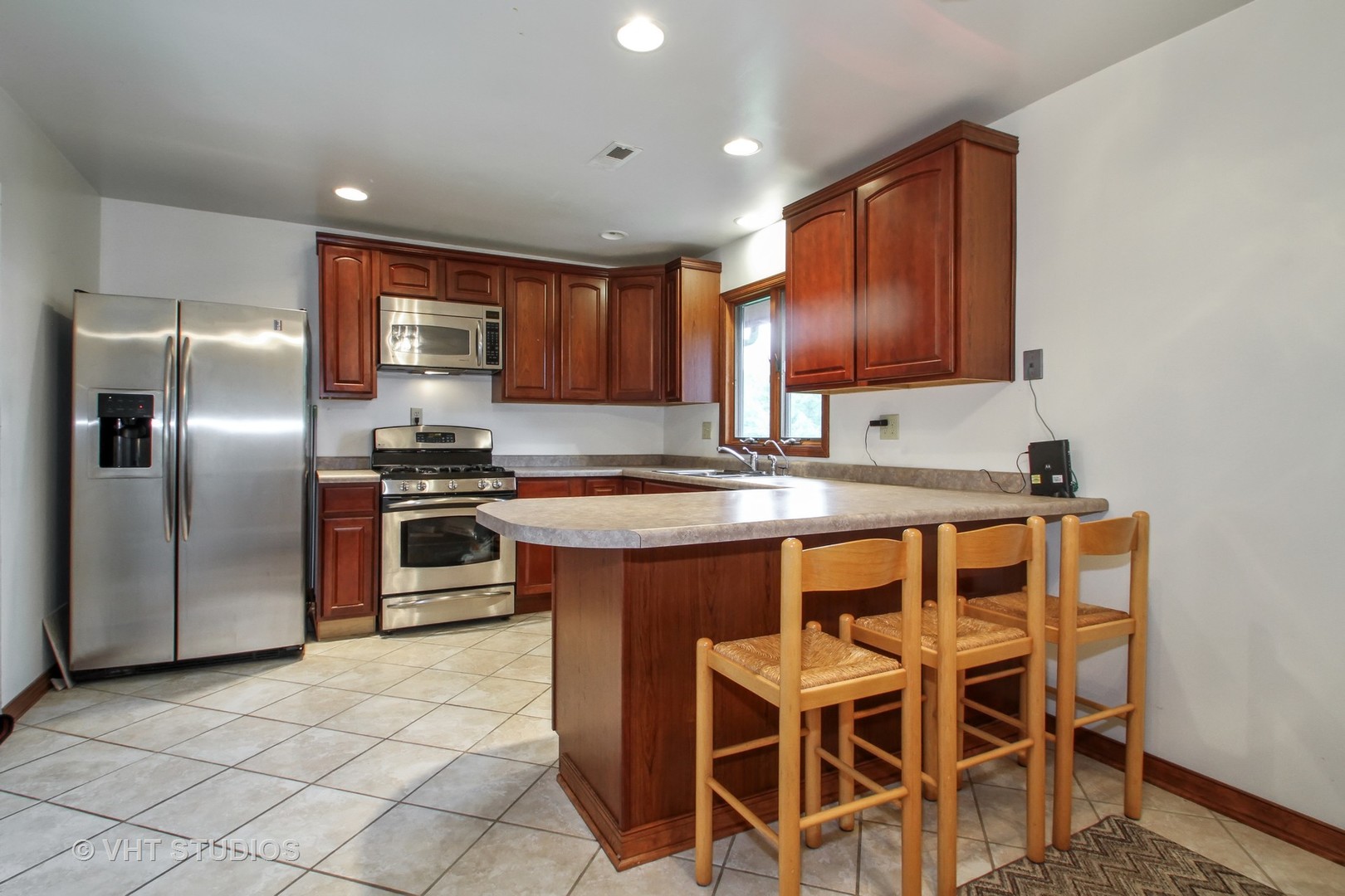 14008 Davis Road Woodstock, IL 60098 - Photo 4 of 32 a kitchen with granite countertop a table chairs microwave and refrigerator