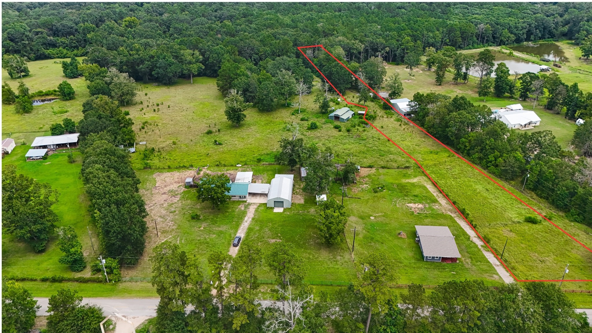 an aerial view of residential houses with outdoor space and trees all around