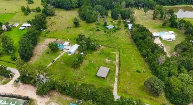 an aerial view of a residential houses with outdoor space and trees all around