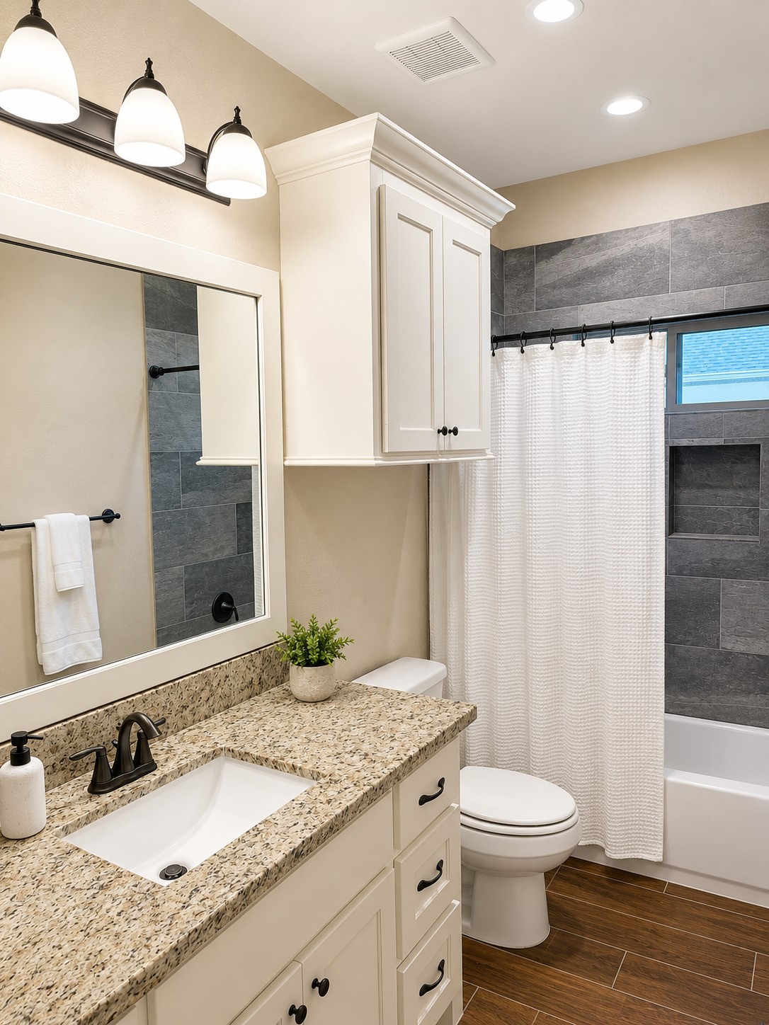 27656 Rio Blanco Drive Splendora, TX 77372 - Photo 15 of 18 This bathroom features a modern design with a granite countertop, under-mount sink, and dark fixtures. It includes a shower-tub combo and ample storage with cabinets. The space is well-lit with overhead lights and has a neutral color palette.