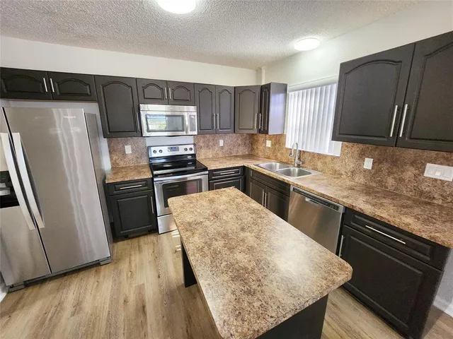 a kitchen with stainless steel appliances granite countertop a refrigerator a sink a stove and oven