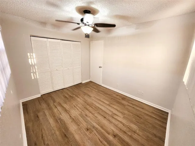a view of a room with wooden floor and a ceiling fan