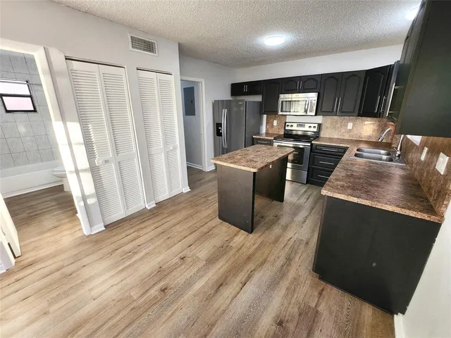 a kitchen with stainless steel appliances granite countertop a refrigerator a stove top oven a sink and dishwasher