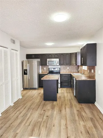 a large kitchen with stainless steel appliances kitchen island a large counter top and a stove